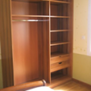 Une armoire en bois de teinte chaude, avec une penderie à gauche et des étagères et tiroirs à droite, installée dans une pièce.